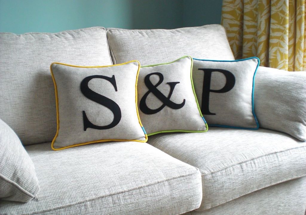 Three grey cushions with a letter on each