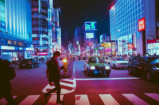 A light up street at night with pedestrian crossing and light boxes.