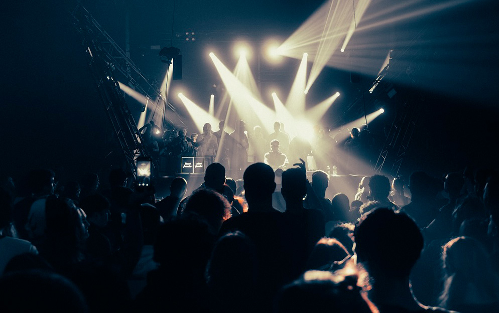 Crowd watching a live performance at Rockhal, together bright stage lights and beams shining over the audience.