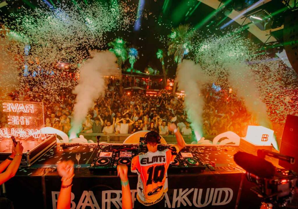 DJ performance in front of a festival crowd at Papaya Club with illuminated event branding around the stage.