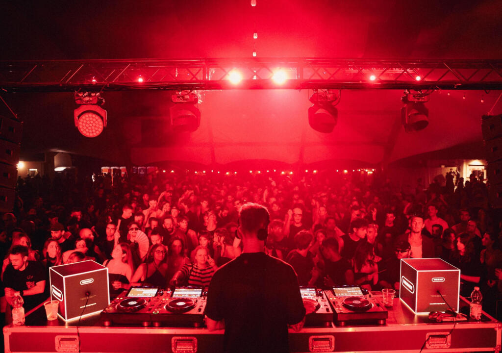 DJ performance in front of a large crowd with two illuminated branded UNIQCUBE light boxes right by DJ booth.