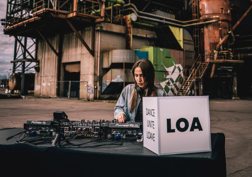 Dj performing beside an illuminated LOA custom cube